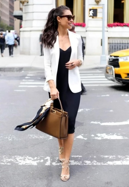 Модный лук: черное платье футляр ниже колен, белый удлиненный пиджак, большая коричневая кожаная сумка с цветным платком, светло-бежевые босоножки с рюшами, солнцезащитные очки и золотые кольца