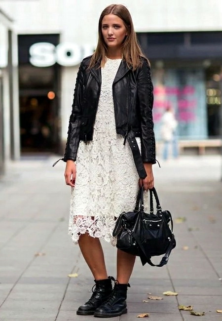 Модный лук: легкое белое платье миди-длины с кружевом, черная кожаная косуха, кожаные черные ботинки на шнуровке и черная кожаная сумка