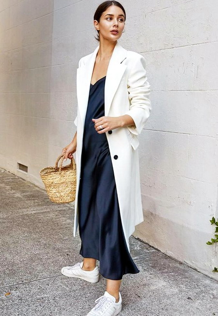 Модный лук: синее платье-комбинация длины макси, длинный белый жакет, белые кроссовки и соломенная сумочка
