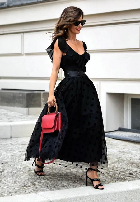 Модный лук: черное вечернее платье с юбкой-пачкой в горошек и воланами на декольте, черные босоножки на шпильке с бантиками, маленькая красная кожаная сумочка, темные солнцезащитные очки и черьги-кольца
