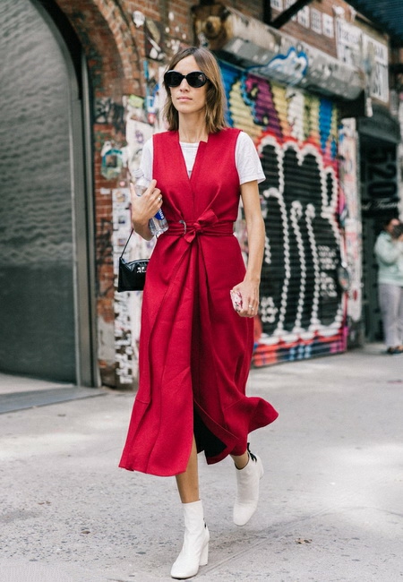 Модный лук: длинное красное платье-жилет с запахом, белая футболка, белые кожаные сапожки, миниатюрная кожаная черная сумочка на ремешке и темные солнцезащитные очки