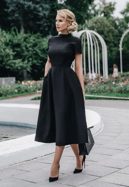 Модный лук: черное строгое платье-миди а-силуэта с короткими рукавами, черные туфли на высокой шпильке и небольшая черная сумочка