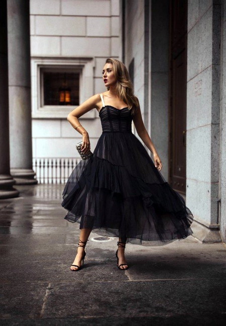 Модный лук: пышное черное платье с корсетом из фатина длины миди, черные босоножки на шпильке с обвязками, вечерний серебристый клатч и золотой браслет