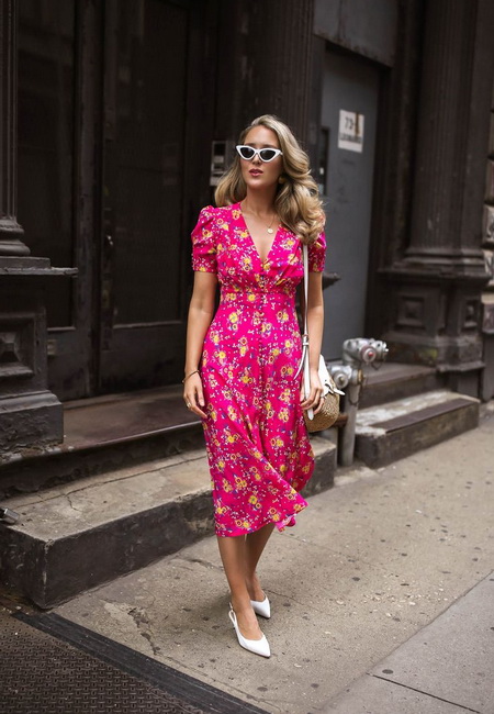 Модный лук: яркое розовое платье в желтый цветочек, белые туфли на каблуке с треугольным носком, бежевая сумочка на длинном ремешке и треугольный солнцезащитные очки в белой оправе