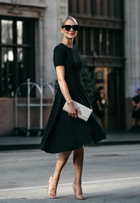 Модный лук: черное строгое платье с пышной юбкой, открытые бежевые босоножки с ремешками, светлый кожаный клатч и черные солнцезащитные очки